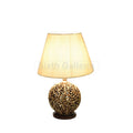 Pair of table lamps with beige fabric shades and ornate carved spherical wooden bases on dark round platforms.