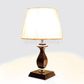 Pair of table lamps with white fabric shades and dark curved wooden bases on square platforms.