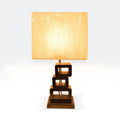 Table lamp with a stacked dark wooden box base and a rectangular beige fabric shade.