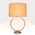 Modern table lamp with circular metal ring base and beige fabric drum shade.